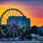 Giant ferris wheel against a city backdrop with the sun setting