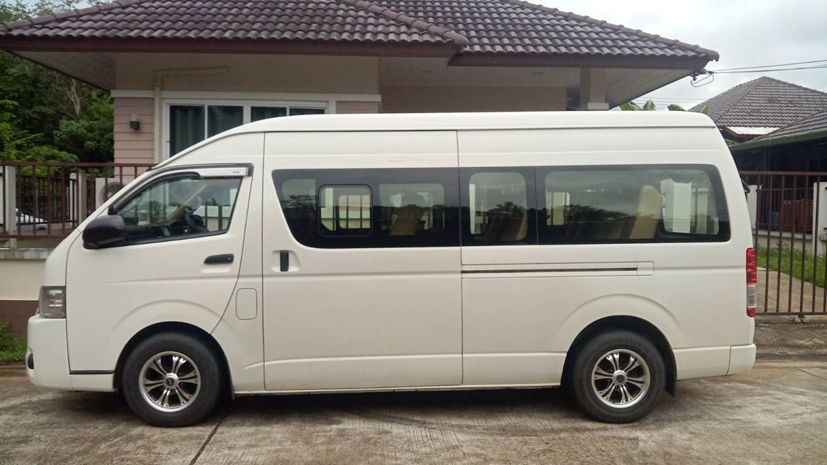Side view of a white minivan parked on a street in front of a building.