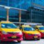 A line of red and yellow Phuket taxis parked outside of Phuket Airport.