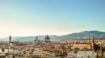 View of central Florence with mountains in the distance and blue skies above.