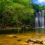 A waterfall flowing into a shallow lagoon with lush green trees along the banks.