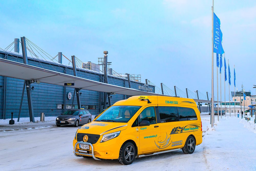 Rovaniemi taxi A yellow Rovaniemi taxi van outside the airport with snow covering the road.