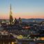 View of Vienna city's skyline at sunset, showing rooftops a large spire.