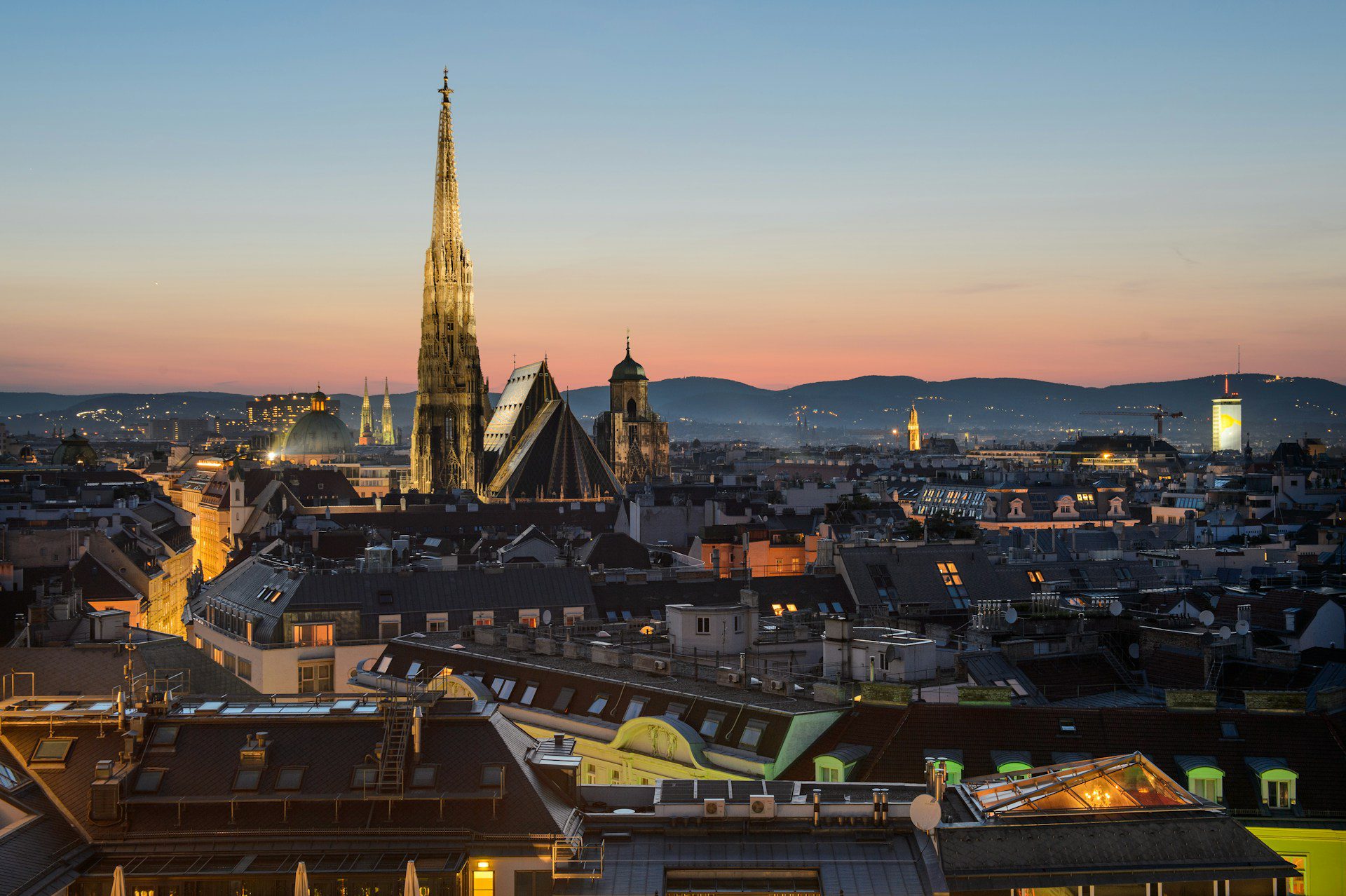 View of Vienna city's skyline at sunset, showing rooftops a large spire.