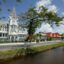 Ornate white building along a grass lined street and creek in Georgetown, Guyana.