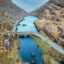 Scenic roadway crossing over blue waters surrounded by rocky hillsides.