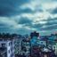 View over city buildings in Dhaka under a cloud covered sky.