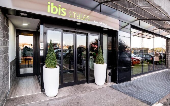 View of the front foor of ibis Styles Roma Vintage, with potted plants either side of the entrance and 'ibis styles' written in yellow on top of the entrance.