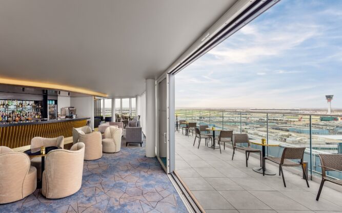 An image of a bar and outdoor terrace with chairs and tables, and a views of a blue sky.