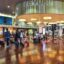 A blurred image of passengers passing through Bergamo Airport with polished floors and a central gathering area.