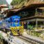 A blue and yellow train stopped outside of Poroy Train Station.