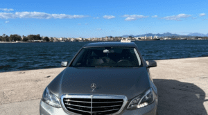 Aktion Taxi - Preveza Taxi Silver Mercedes parked in front of a waterway.