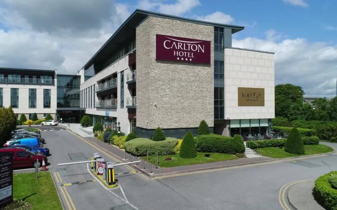 A side view of the Carlton Hotel at Dublin Airport with the purple hotel logo on the side of the building.