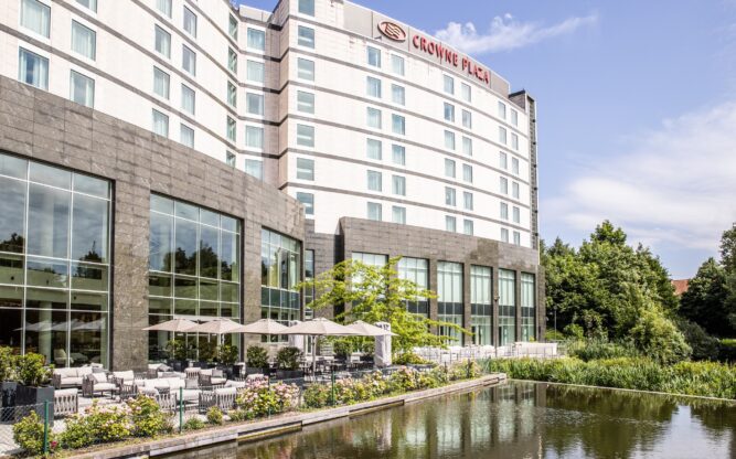 The Crowne Plaza Brussels Airport Hotel with a water feature and flower beds along the front.
