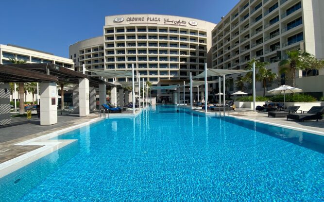 Exterior of the Crowne Plaza, with a large swimming pool in front.