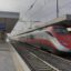 A red and silver train pulling into the Lamezia Terme Centrale station.