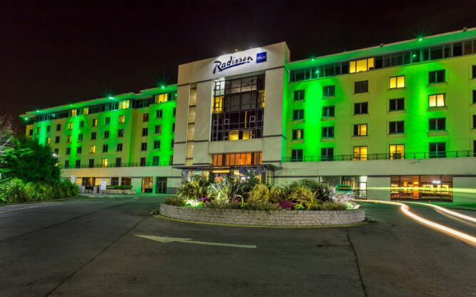 A photo of Radisson Blu Hotel at Dublin Airport at night with fluro green downlighting across the front facade