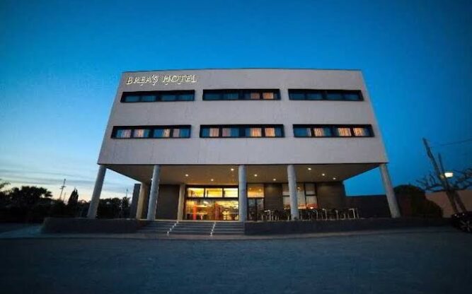 Exterior of Brea's Hotel at night, with a lit up sign on the top left corner of the building.