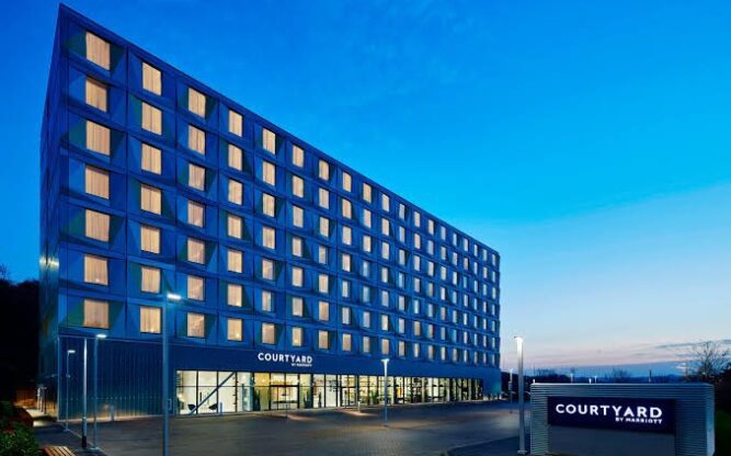 Exterior of the Courtyard Marriott Hotel at Luton Airport, in the evening with the windows lit up.
