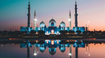 The Grand Mosque in Abu Dhabi at night, with a large body of water in front.