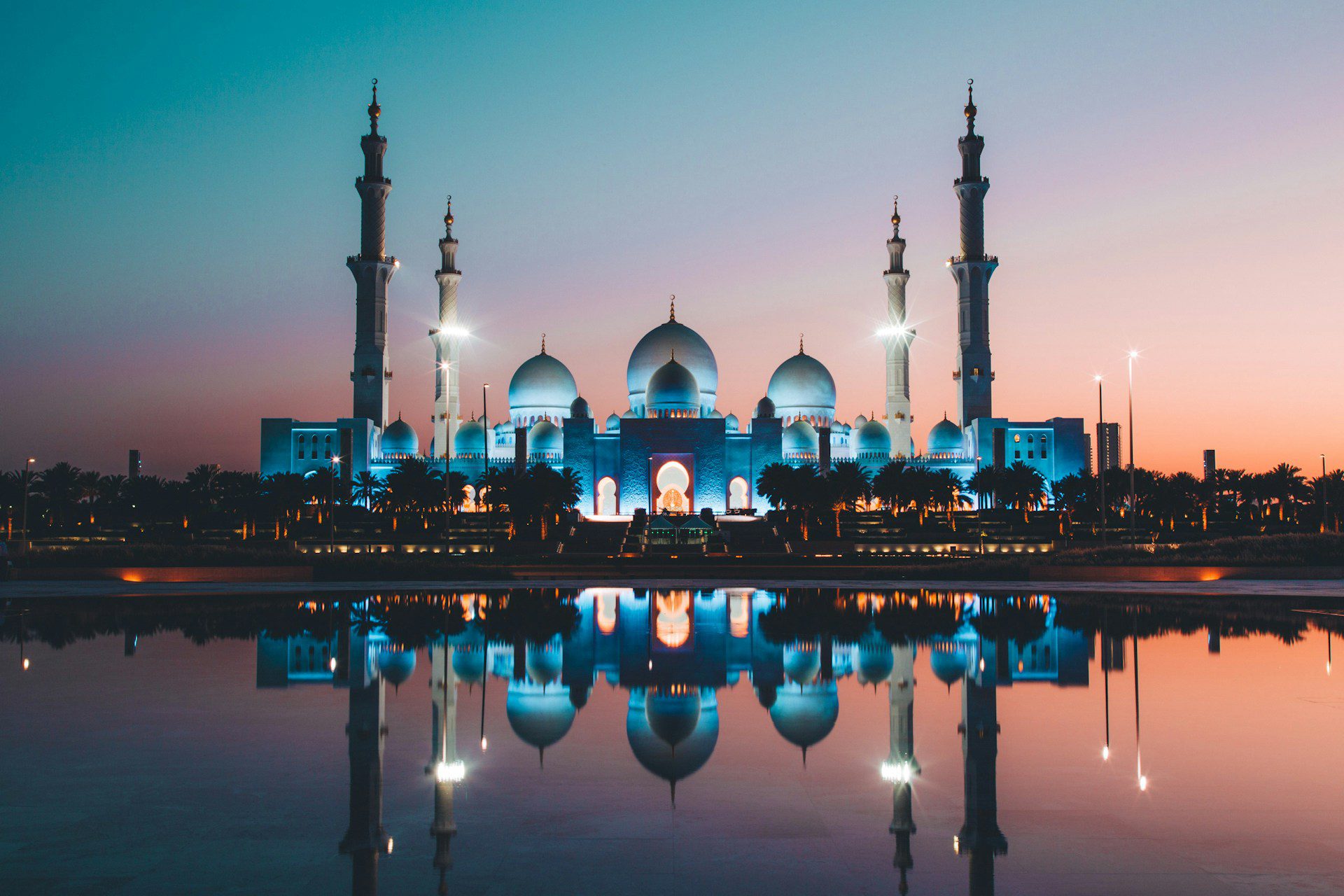 The Grand Mosque in Abu Dhabi at night, with a large body of water in front.