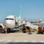 A Transavia plane on the tarmac, with staff loading luggage into the plane, and blue skies above.