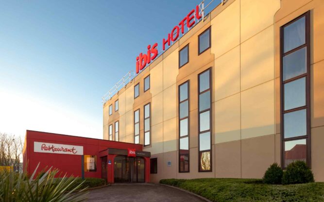 A side view of the cream and brown ibis Brussel Airport Hotel with red signage