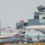 Exterior of Prague Airport Terminal, with a plane in front and grey skies above.