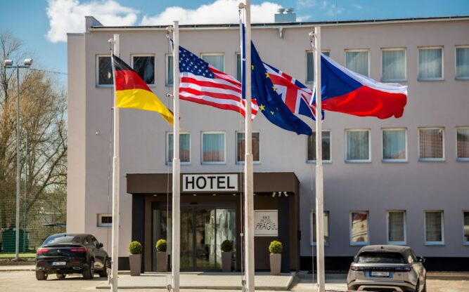 Exterior of Sky Hotel Prague, showing a white building with four flags flying in front.