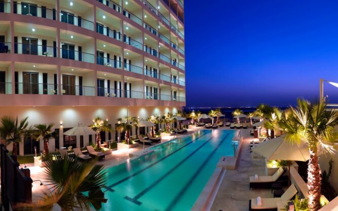 Exterior of Staybridge Suites Yas Island at night, with a swimming pool in front.