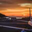 Planes parked on the tarmac at Gran Canaria Airport, with an orange sunset sky above.