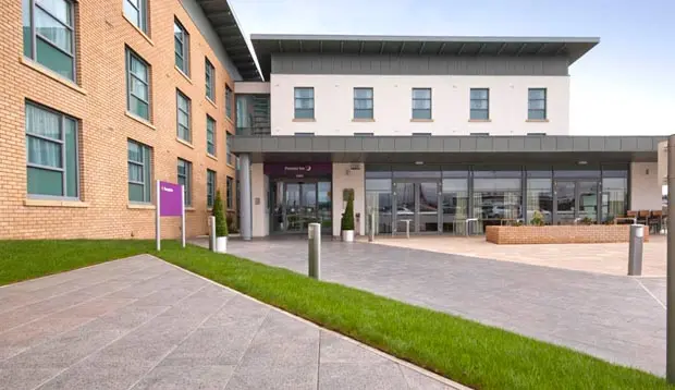 A side view of the Premier Inn Edinburgh Airport Hotel with brown brick walls and a white entrance area.