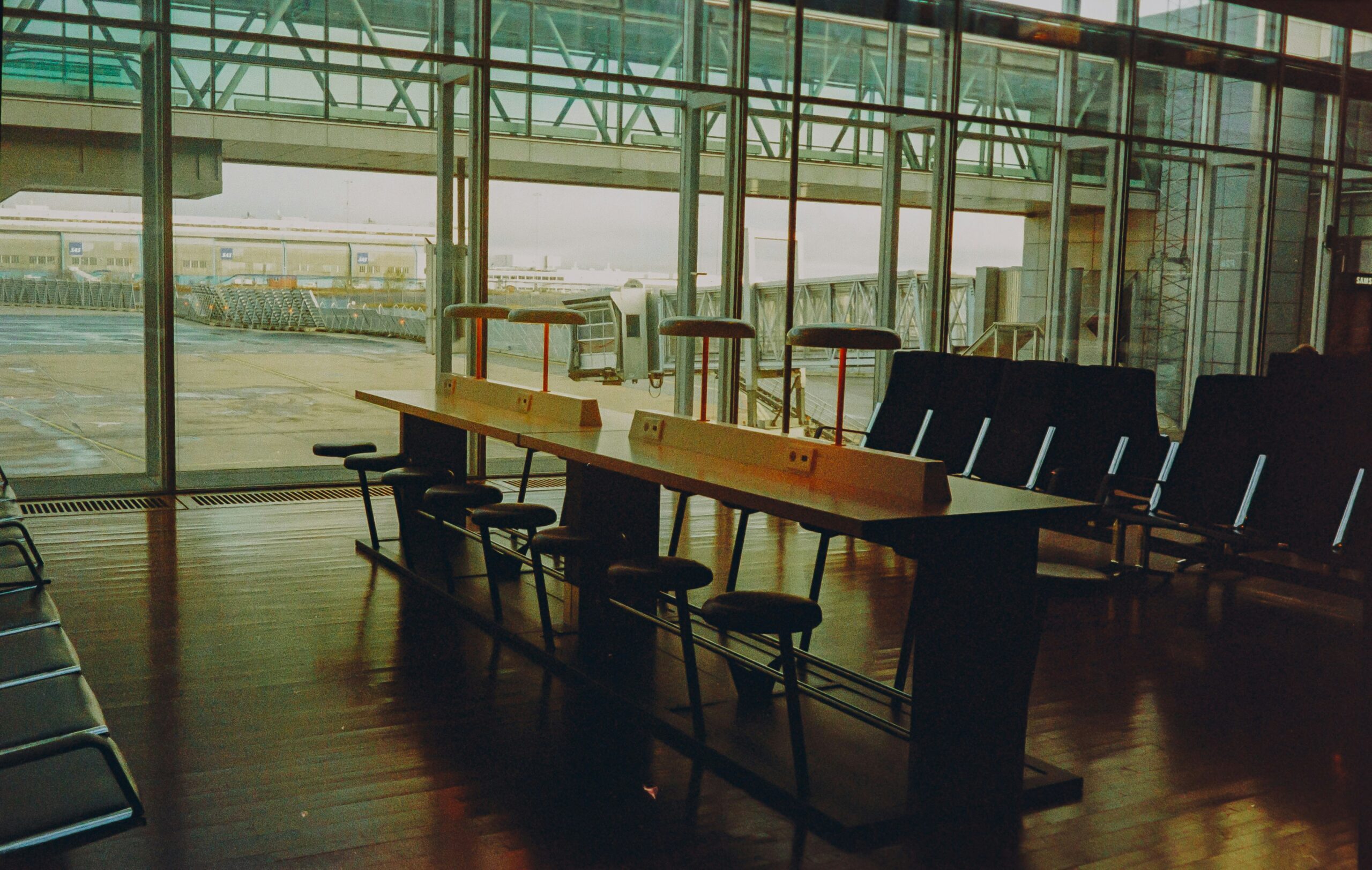 A waiting area at Stockholm Airport Arrivals with benches, chairs and workstations.