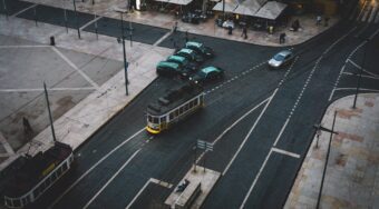 Aerial view of a street in Lisbon, with a tram and various vehicles on the road.