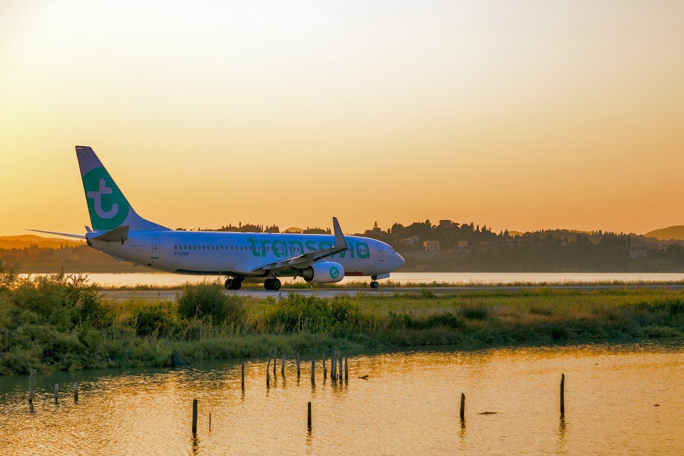 A plane landing at sunset at Corfu Airport.