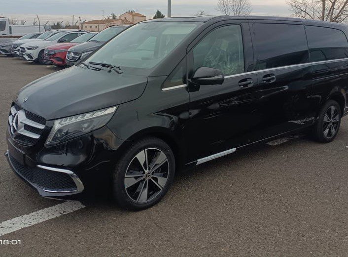 Side view of a black Girona Airport taxi minivan parked in an outside car park.