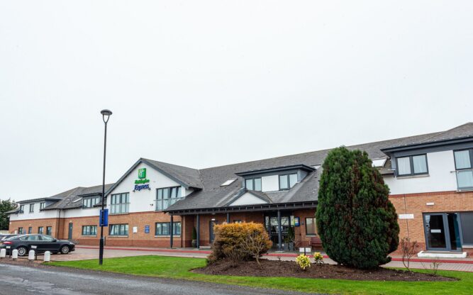 The Holiday Inn Express Edinburgh Airport Hotel with a brown brick lower storey and white upper storey.