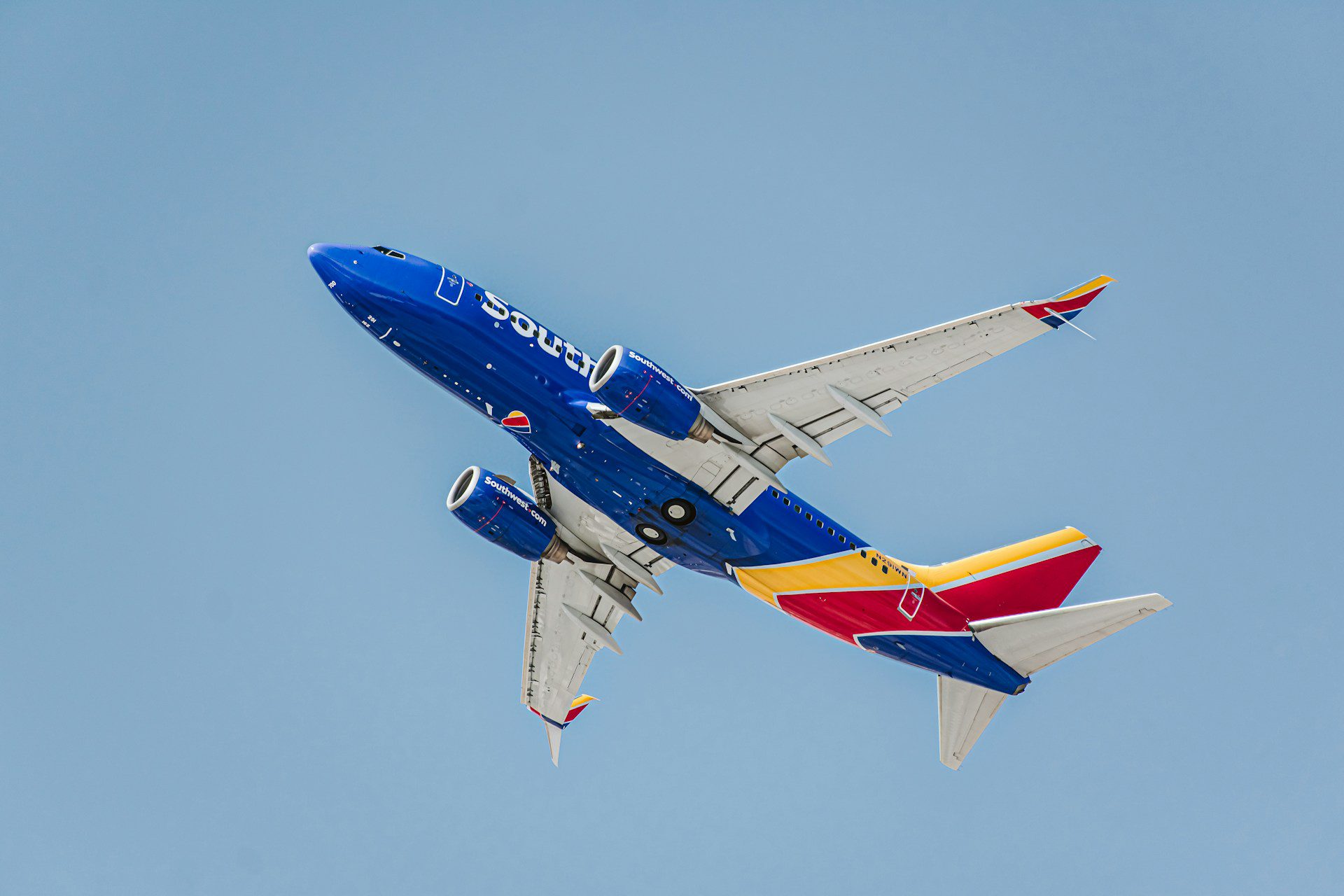 A blue aeroplane with a yellow and red stripe on the tail wing taking off from Las Vegas Airport