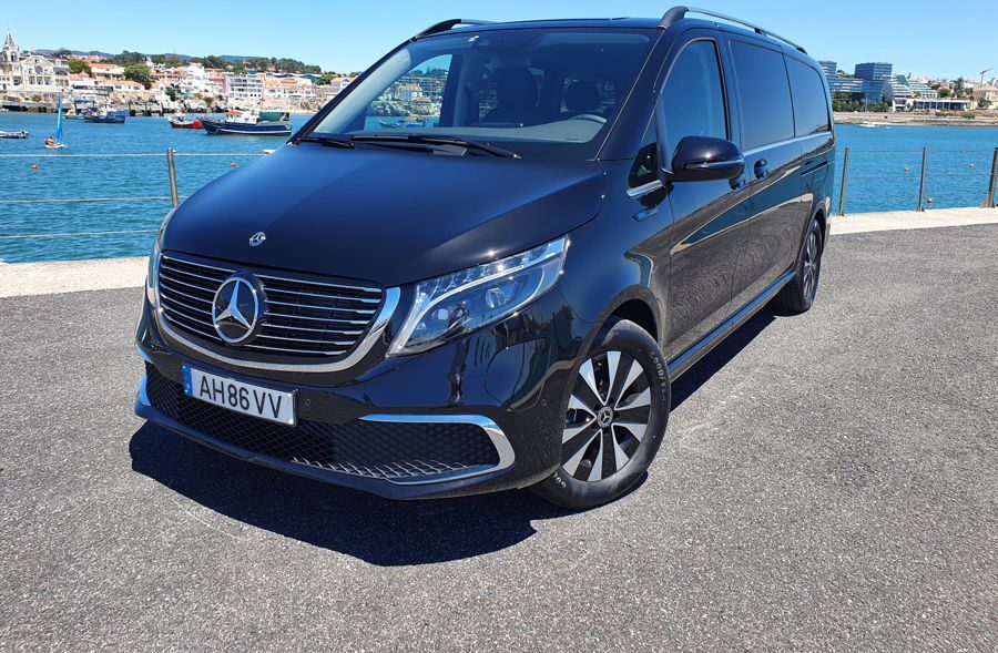 A black minivan taxi, Lisbon Airport, parked near the sea.