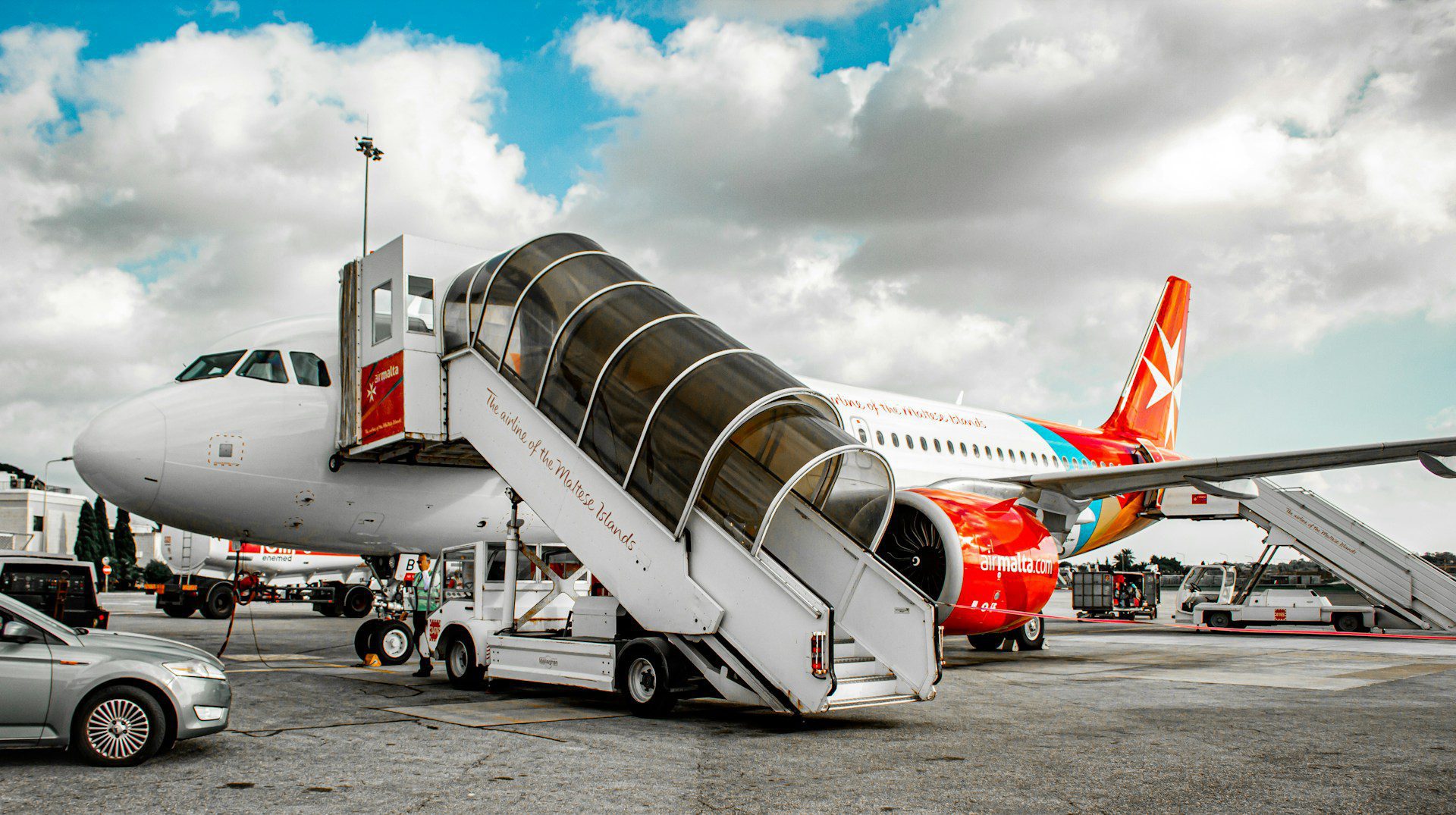 An aircraft ready to embark passengers via an external staircase on the runway at Malta Airport.