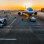 A plane parked at one of the Porto Airport gates with the sun rising behind it.