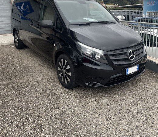 A black Ciampino Airport taxi minivan parked outside of a building.