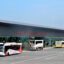 Front view of the main terminal at Tirana Airport, with buses parked outside and blue skies above.