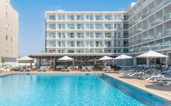 Modern exterior view of Alua Leo Mallorca hotel on a sunny day, featuring a large outdoor swimming pool surrounded by sun loungers and white parasols, with the hotel’s multi-story glass balconies overlooking the courtyard.