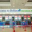 A photo taken just inside the Belfast International Airport showing a roped-off check-in line in front of the airline counters with a welcome sign above them.