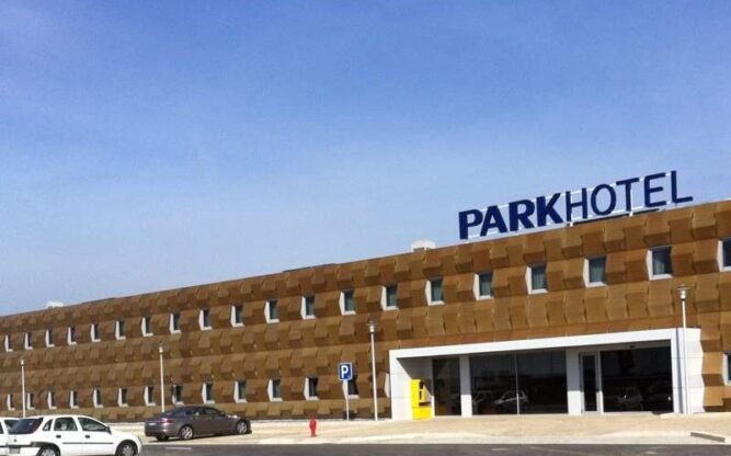 The front facing view of the long brown Park Hotel at Porto Airport with a blue sign on top of the building.