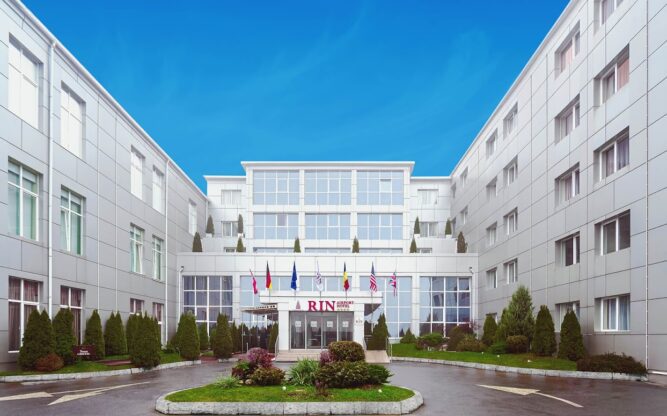 The impressive open-rectangular entrance with a commanding garden and white walls leading to the RIN Airport Hotel at Bucharest Airport