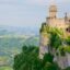 A side view of the San Marino castle built into the side of a mountain overlooking a valley.