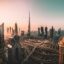 A panoramic view of downtown Dubai at sunset, featuring the Burj Khalifa and a network of highways, illustrating the urban landscape travelers navigate during an airport transfer in Dubai.