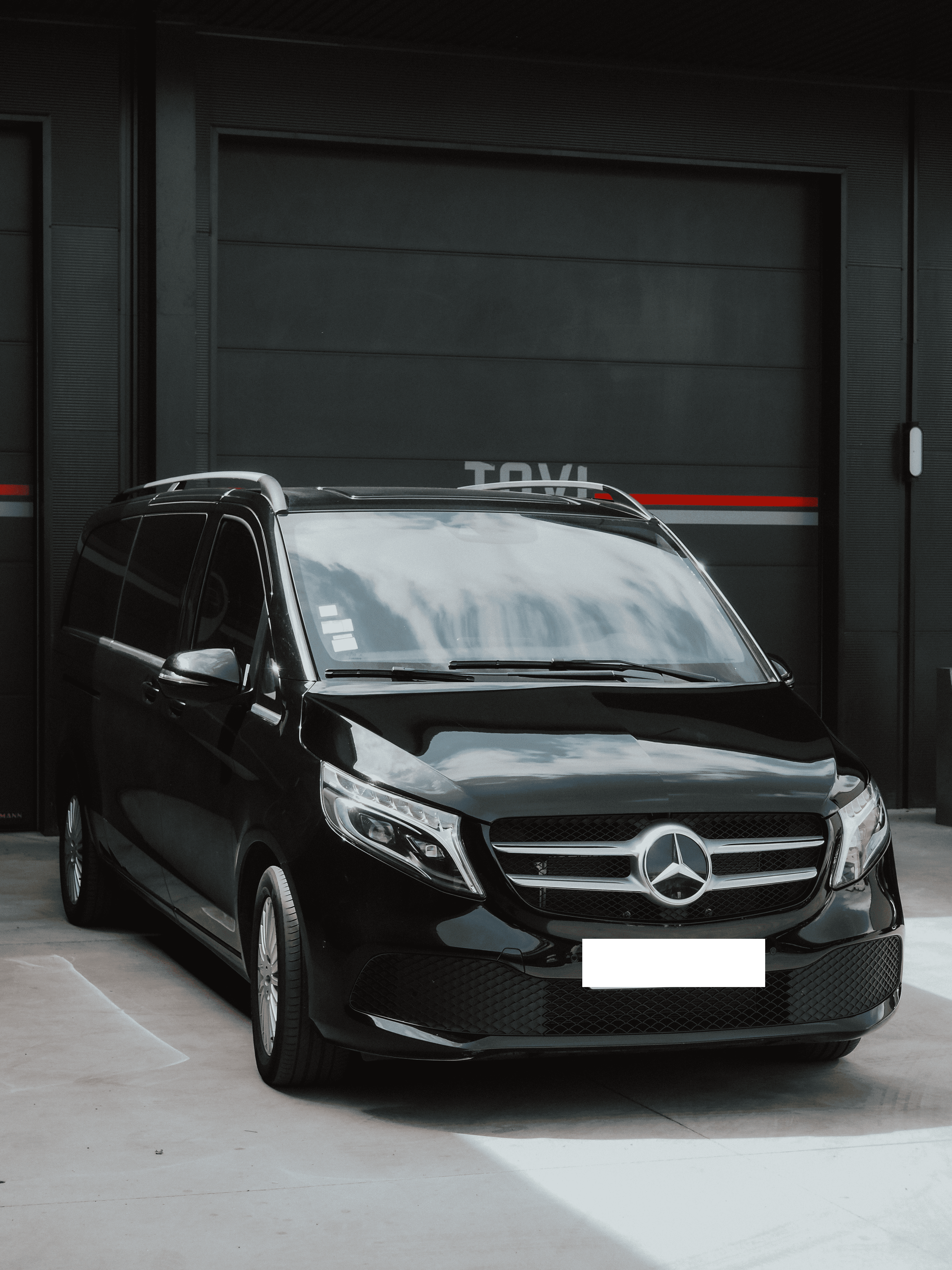 A luxurious black minivan cab is parked outside.